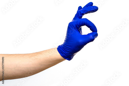 a hand in blue medical surgical glove shows okay gesture on white background