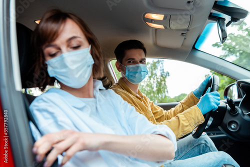 man and woman in medical masks and protection gloves sitting in car during coronavirus pandemic, selective focus © LIGHTFIELD STUDIOS
