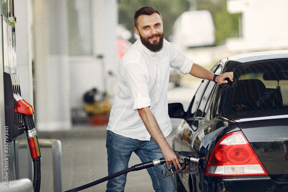 Man on a gas station. Guy refuelong a car. Male in a white shirt. Man on a gas station. Guy refuelong a car. Male in a white shirt.