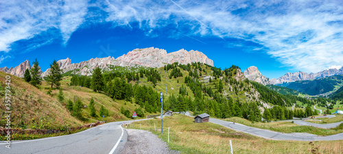 Panoramic view made from Passo Gardena of magical Dolomite peaks of Cima Cunturines and serpentine mountain road, South Tyrol, Italy, wide angle