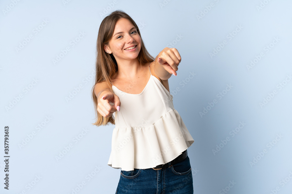 Young Lithuanian woman isolated on blue background pointing front with happy expression Young Lithuanian woman isolated on blue background pointing front with happy expression
