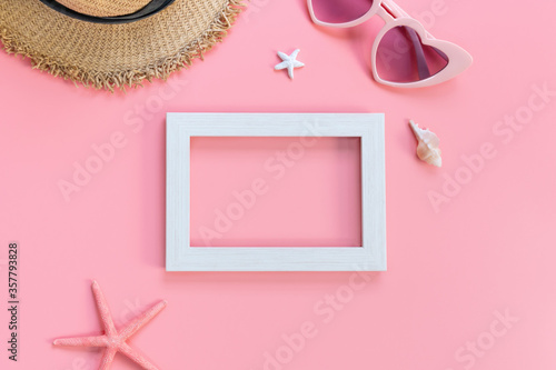 Top view of white frame, sunglasses, straw hat on pink color background, travel concept. Flat lay , copy space