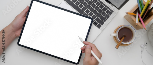 Female entrepreneur using blank screen tablet while working with laptop on white office desk