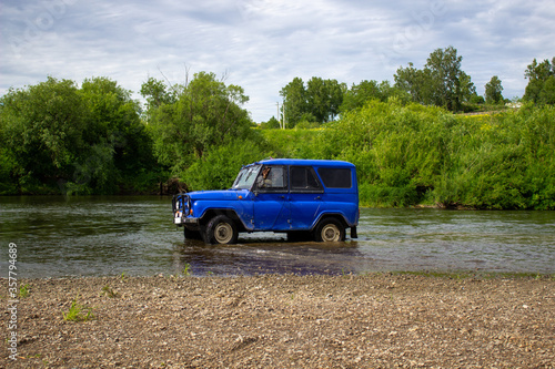 Car SUV UAZ rides on the river.