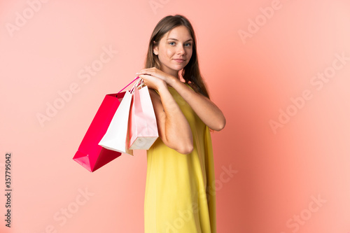 Young Lithuanian woman isolated on pink background holding shopping bags