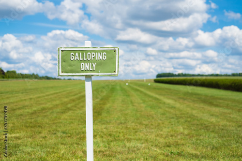 Shallow focus of a Galloping Only sign seen adjacent to a huge grass expanse. Used for horse-racing training.