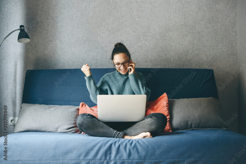 A girl works from home or a student is studying from home or a freelancer. She uses a laptop and a phone.