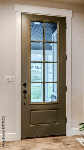 Vertical Hinged front door with glass pane viewed from interior of home with wood floor