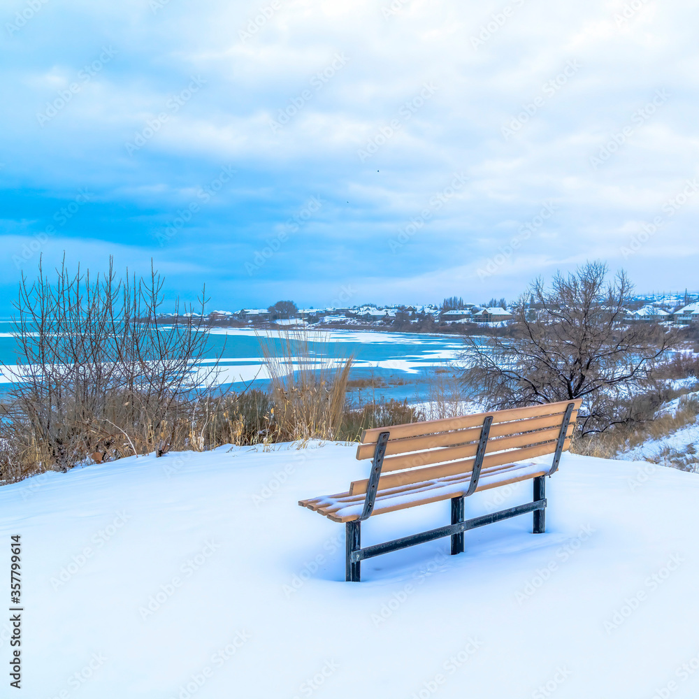 Square Bench on a snowy terrain with frozen Utah Lake and overcast sky view in winter