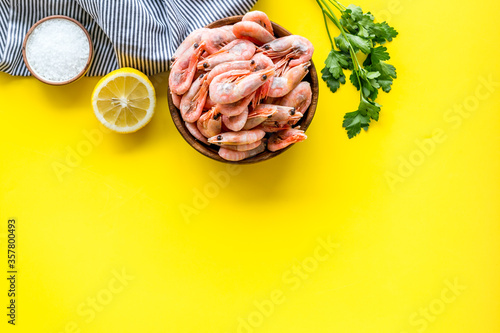 Shrimps for mediterranean salad - with lemon and greeenery - on yellow desk top view copy space photo