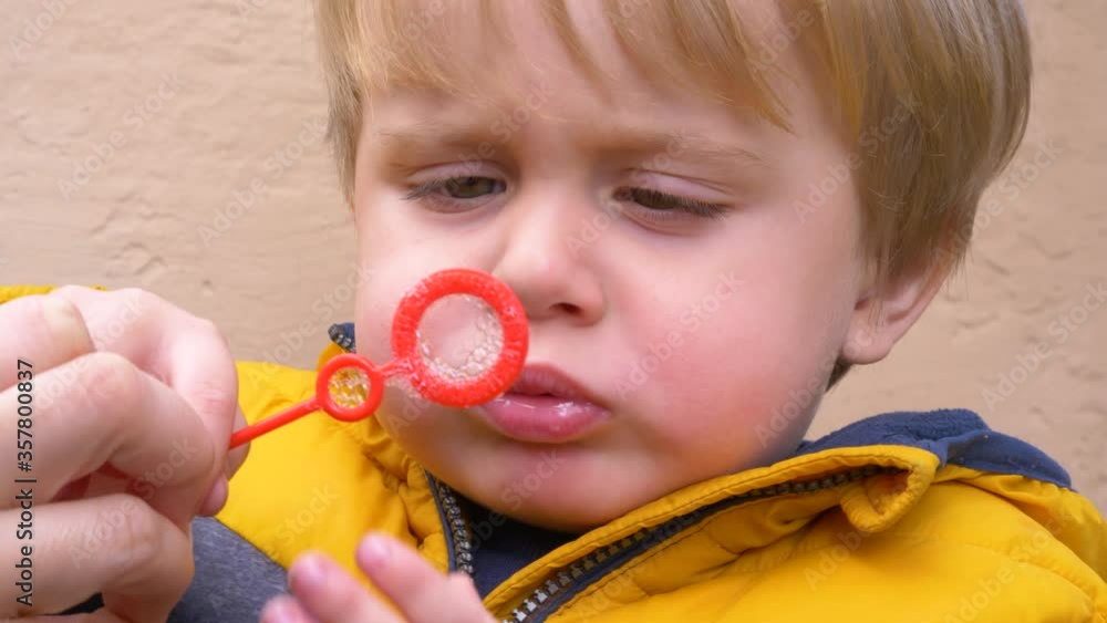 beautiful blond boy playing with soap bubbles on the terrace of his house beautiful blond boy playing with soap bubbles on the terrace of his house