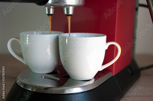 Two cups of espresso, preparing coffee process, red coffee machine.