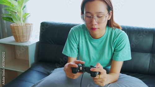 Young Asian women buying games via credit card While playing games on the sofa in the living room in the house. photo