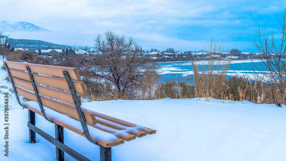 Panorama Empty outdoor bench on snowy terrain overlooking frozen Utah Lake in winter