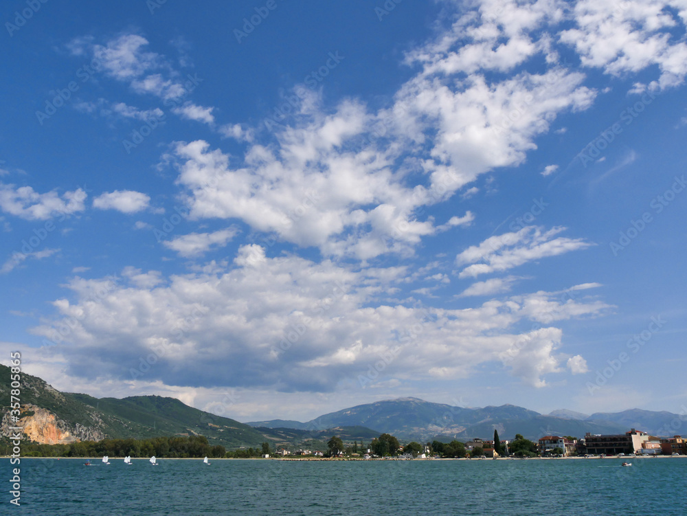 Optimist navegando en la bahía de Vonitsa, Grecia con montañas y nubes