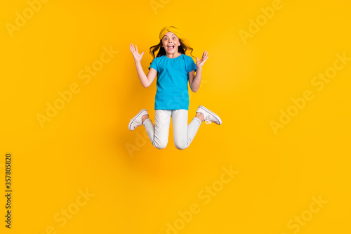 Full size photo of crazy little lady jump high good mood celebrate competition winning unbelievable wear casual blue t-shirt headband trousers shoes isolated yellow color background