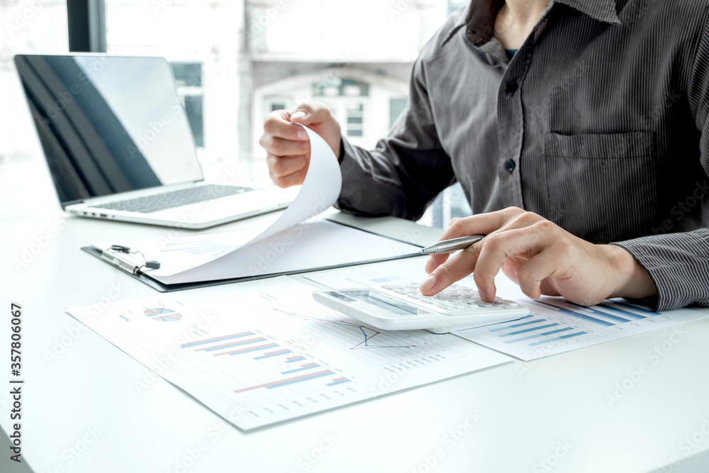 Business man calculate financial graphs that show results and analyze financial arrangements for business investment Business man calculate financial graphs that show results and analyze financial arrangements for business investment