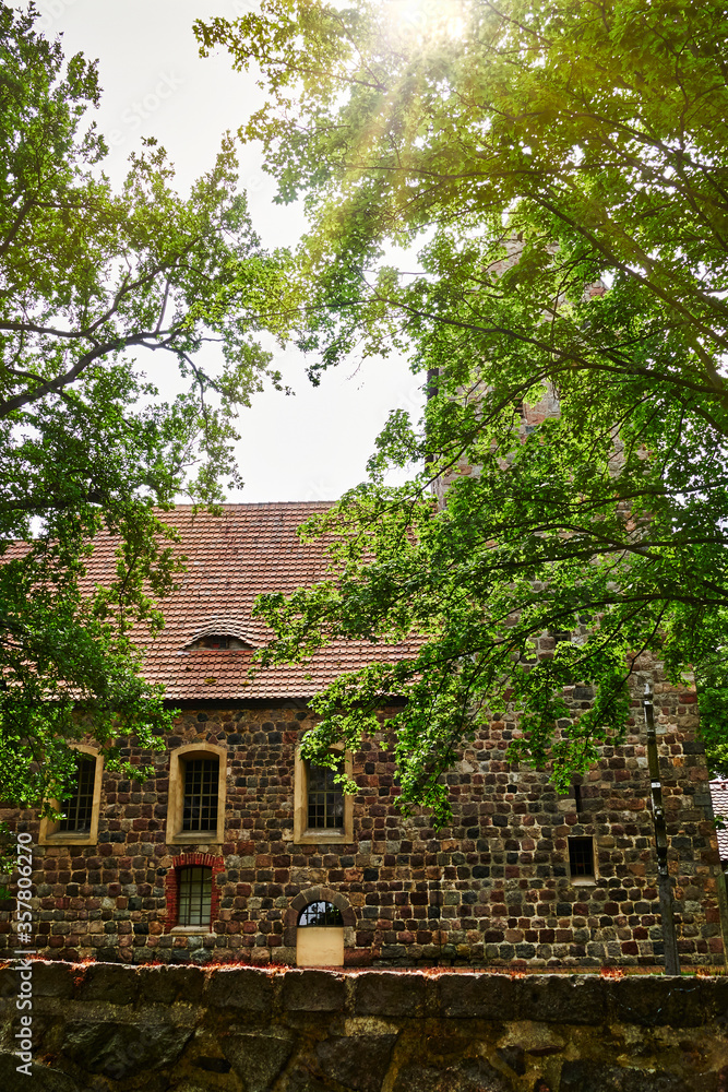 Details of a historic medieval church in Berlin, Germany. You can see parts of the building made of field stones, framed by trees. Details of a historic medieval church in Berlin, Germany. You can see parts of the building made of field stones, framed by trees.