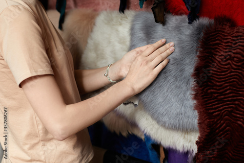 woman in warehouse of fur. different types of multicolored fur skins.