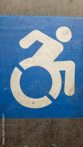 Vertical Close up of blue and white handicapped sign painted on a gray surface