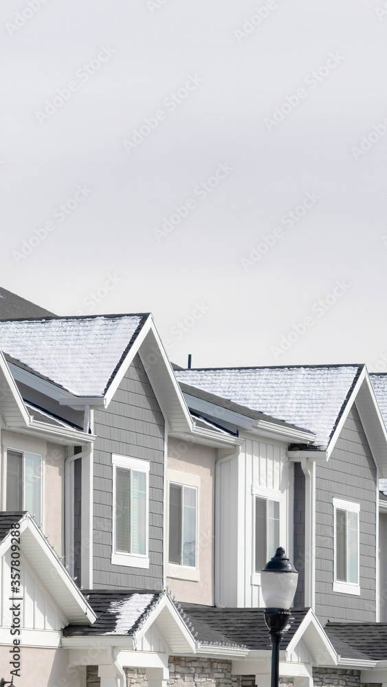 Vertical Facade of townhouses in South Jordan Utah with snowy gable roofs in winter Vertical Facade of townhouses in South Jordan Utah with snowy gable roofs in winter