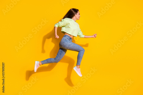 Full size profile side photo of cheerful girl jump run fast speed hurry season discounts wear good look clothes gumshoes isolated over shine color background