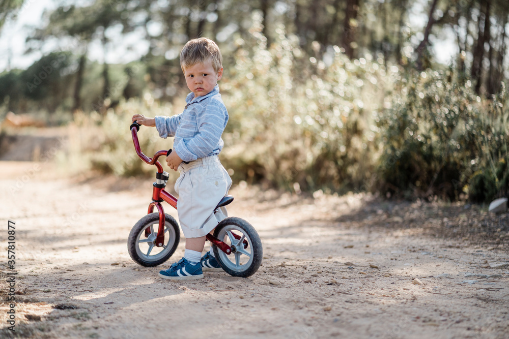 Cute toddler riding bicycle on the dirt road