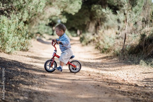 Fototapeta Naklejka Na Ścianę i Meble -  Cute toddler riding bicycle on the dirt road