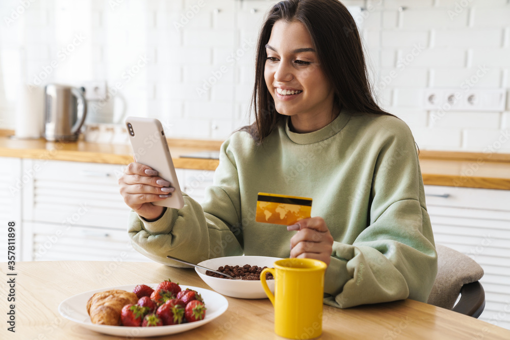 Photo of smiling woman using mobile phone and holding credit card Photo of smiling woman using mobile phone and holding credit card