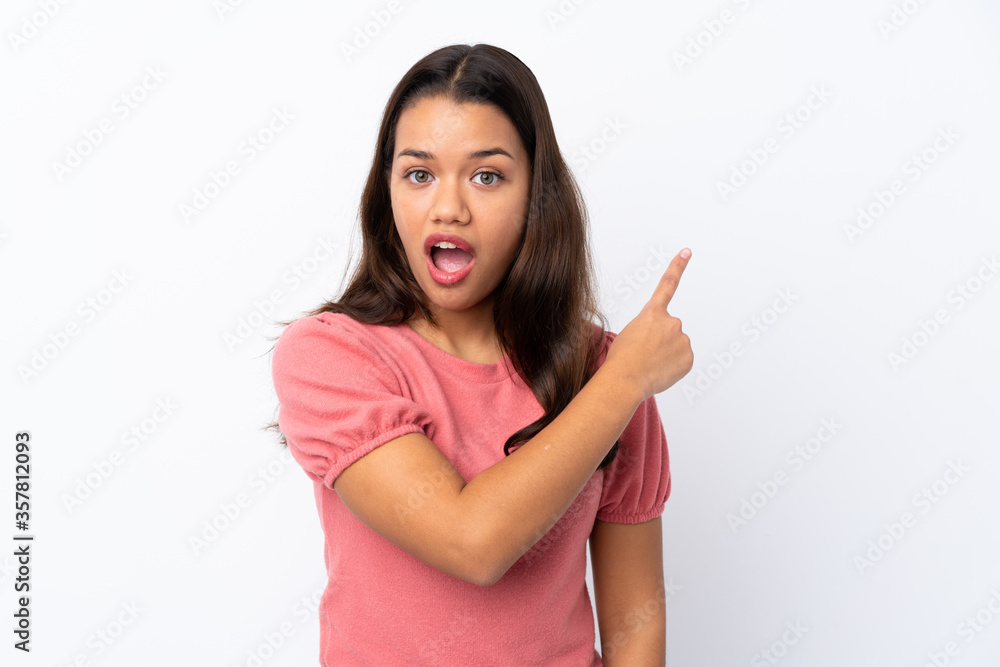 Young Colombian girl over isolated white background surprised and pointing side Young Colombian girl over isolated white background surprised and pointing side
