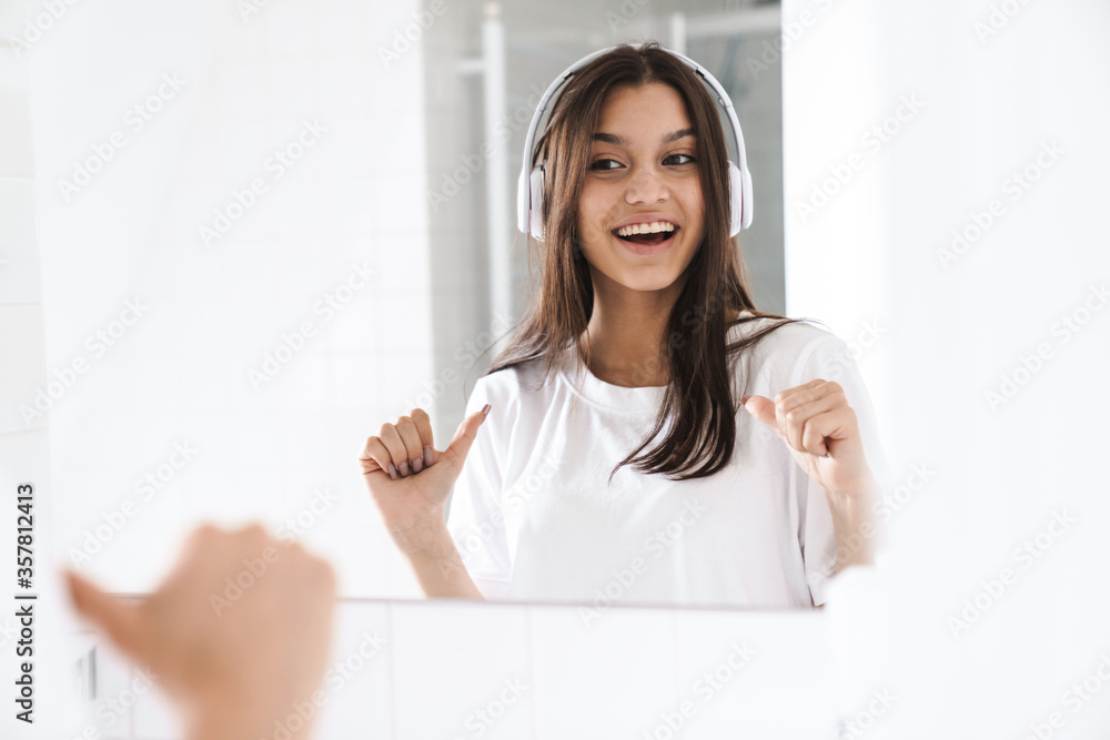 Photo of woman pointing finger at mirror while using wireless headphone Photo of woman pointing finger at mirror while using wireless headphone