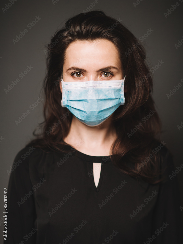 Portrait of an woman in a medical mask. The background is dark. Portrait of an woman in a medical mask. The background is dark.