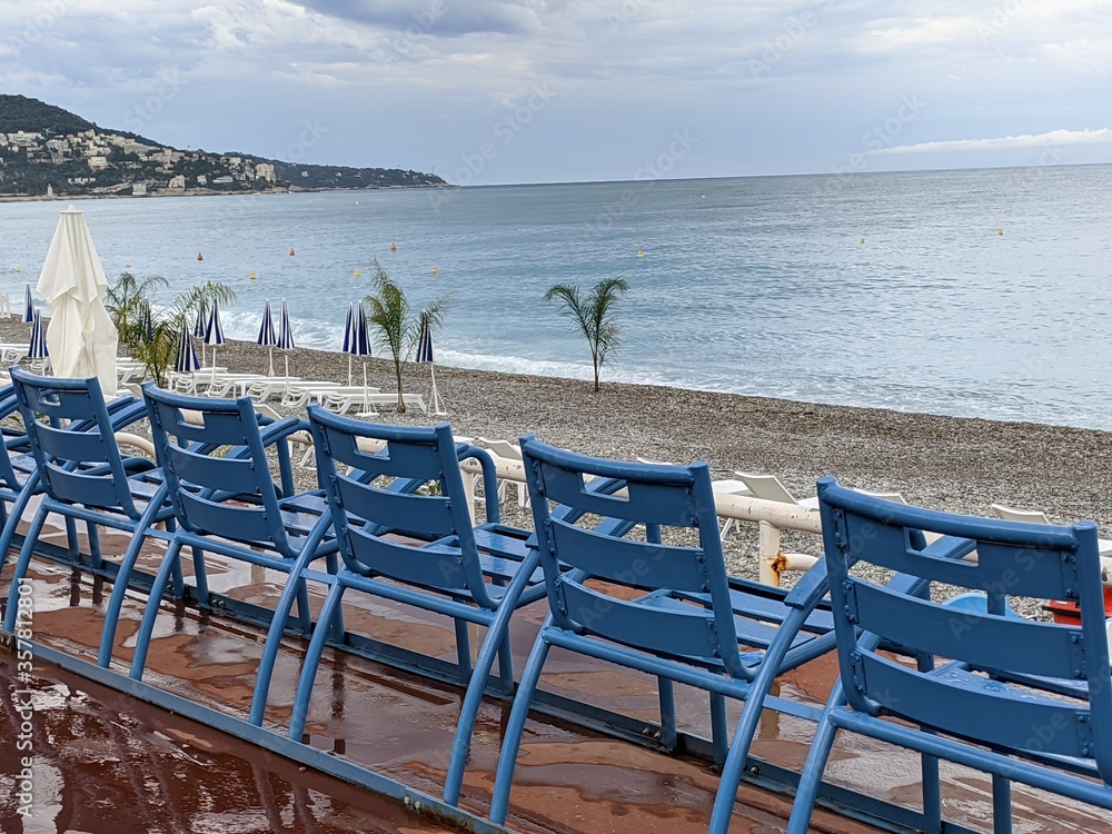 Nice la promenade des anglais avec la mer méditerranée et la côte d'azur en france, chaise banc bleu turquoise richesse et luxe avec grand hotel en bord de plage