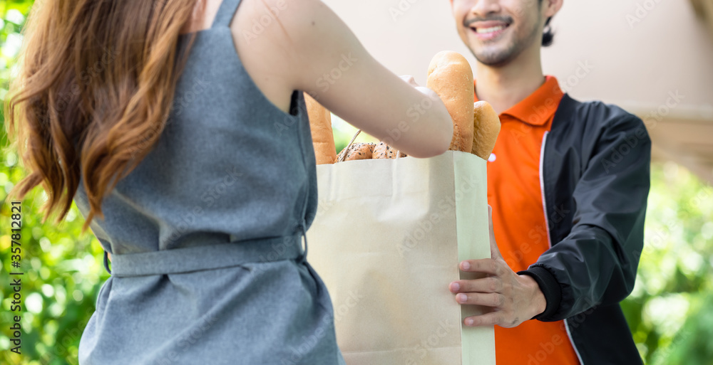 Delivery man in orange uniform pick up food for delivery at restaurant