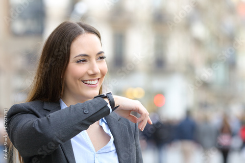 Valokuva Happy entrepreneur dictates message on smartwatch in the street