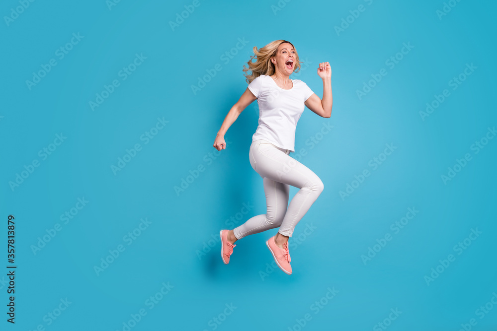 Full size profile side photo of enthusiastic crazy funky funny woman hear incredible discounts jump run hurry fast speed wear stylish trendy clothes isolated over blue color background