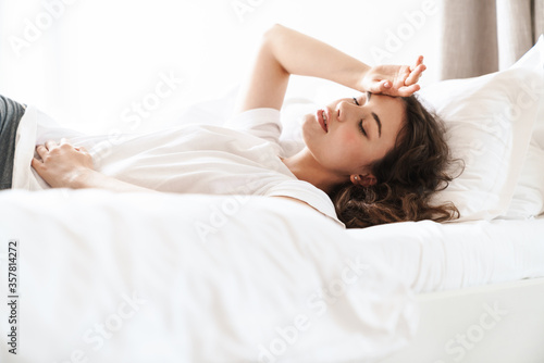 Photo of pretty brunette beautiful woman lying on bed after sleep