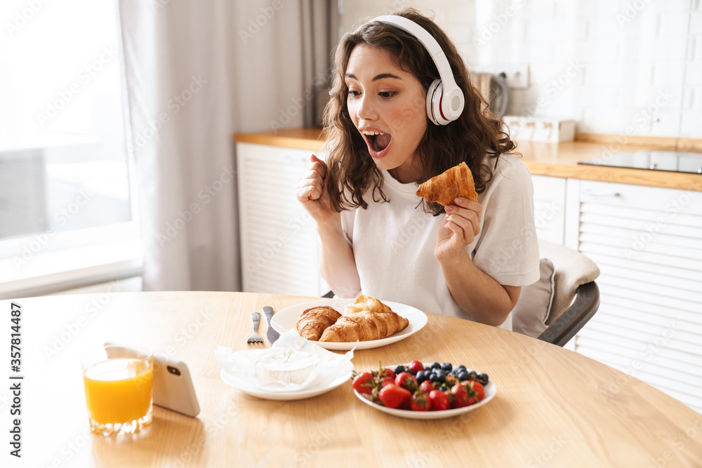 Photo of woman watching movie on mobile phone while having breakfast Photo of woman watching movie on mobile phone while having breakfast