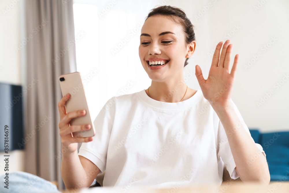 Photo of joyful beautiful woman using mobile phone and waving hand Photo of joyful beautiful woman using mobile phone and waving hand
