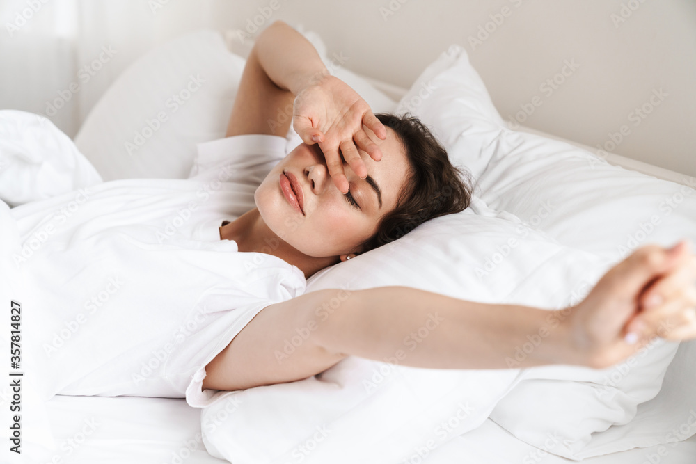 Photo of pretty young woman stretching her body while lying on bed Photo of pretty young woman stretching her body while lying on bed