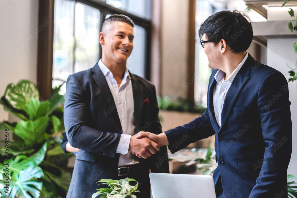 Image two business partners in elegant suit successful handshake together in modern office.Partnership approval and thanks gesture concept Image two business partners in elegant suit successful handshake together in modern office.Partnership approval and thanks gesture concept