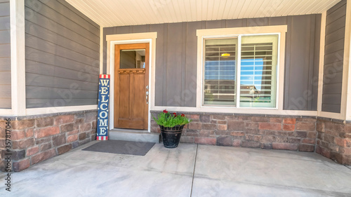 Panorama crop Home entrance with concrete porch brown wooden front door welcome sign