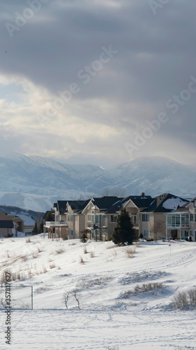 Vertical frame Homes on snowy terrain ovelooking Wasatch Mountain peak and dark overcast sky