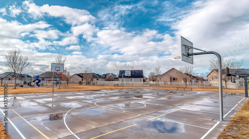 Panorama crop Leisure park with basketball courts and playground against neighborhood homes