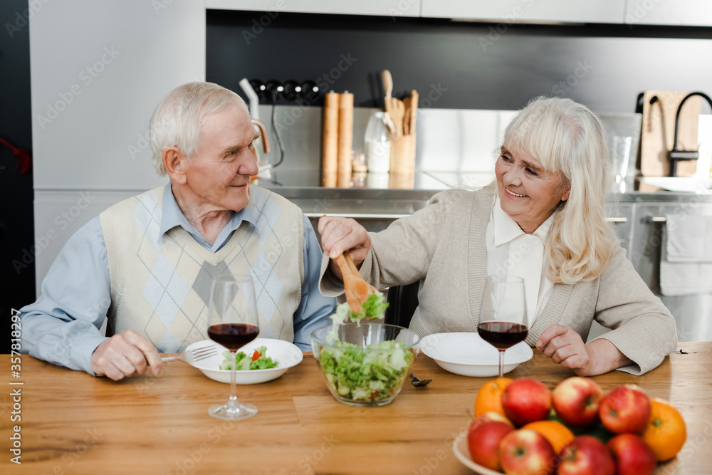 happy senior wife and husband having dinner with wine and salad at home on quarantine happy senior wife and husband having dinner with wine and salad at home on quarantine