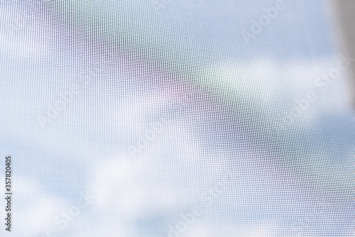 Background view from the window with a mosquito net on the sky with clouds and a rainbow.
