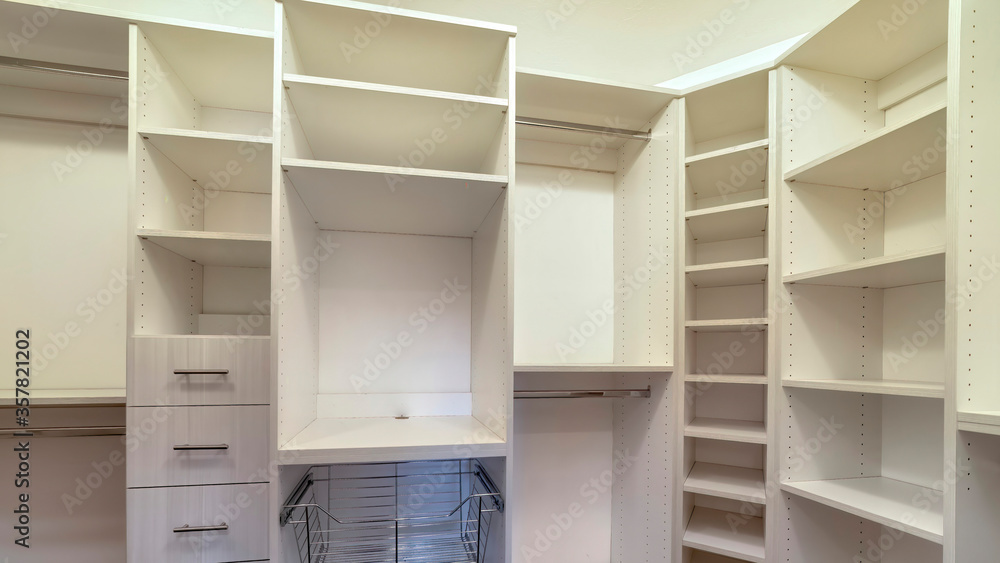 Panorama Walk in closet interior with shelves hanging rods drawers and metal baskets