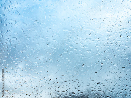 Wet window with rain drops and a cloudy sky outside.