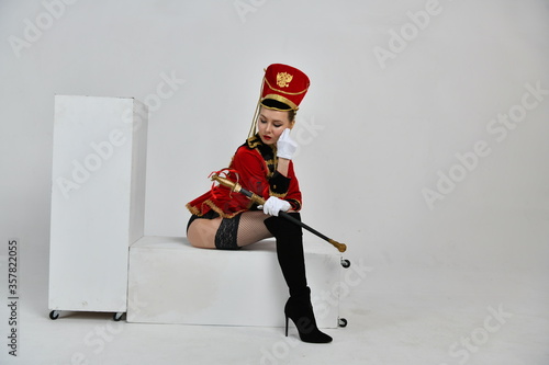 Fotografie beautiful girl in a red hussar costume with a sword
