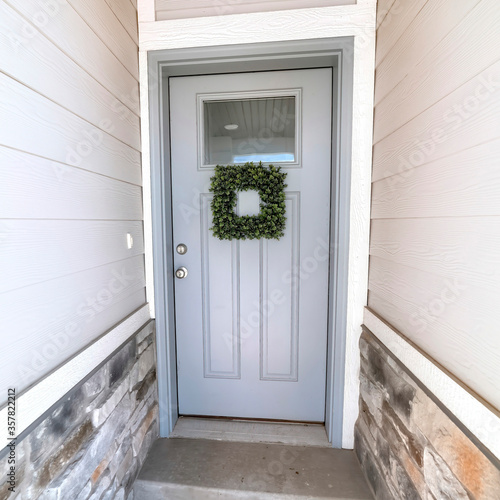Square frame Square leafy wreath on front door entrance with glass pane and transom window